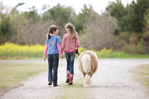 Caucasian girls walking pony on dirt path Stock Photos