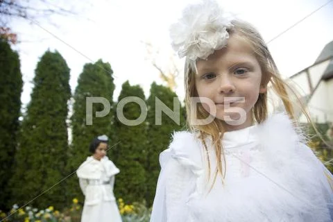 Caucasian girls wearing white dresses walking in garden Stock-Fotos