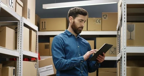 Caucasian good looking young postman standing in postal store with parcels and 스톡 동영상 125214529
