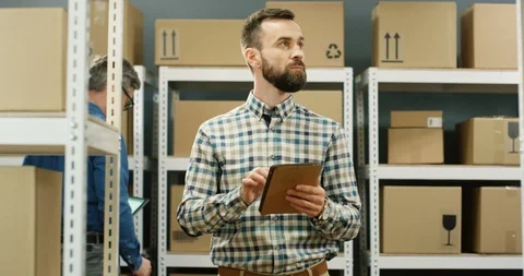 Caucasian good looking young postman standing in postal store with parcels and 스톡 동영상 126596924