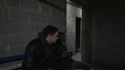 Caucasian guy and black guy are sitting in a bomb-shelter during russian Stock Footage 171345701
