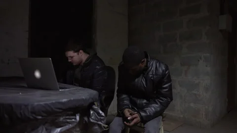 Caucasian guy and black guy are sitting in a basement during a bombardment Stock-Footage 171347856
