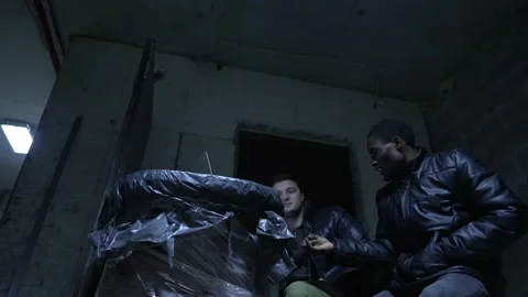 Caucasian guy and black guy are hiding in a basement during a war and discuss Stock Footage 171348338