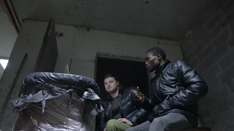 Caucasian guy and black guy are hiding in a basement during a war and Stock Footage 171348428
