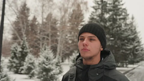 Caucasian guy with backpack in snowy park scene. Young Caucasian male with Stock Footage 335407065