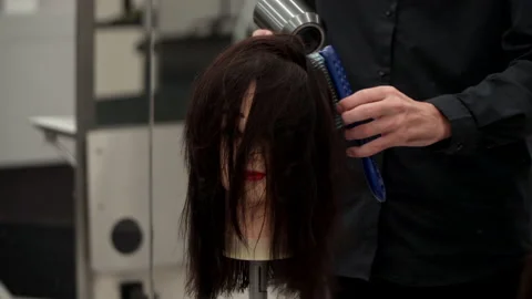 Caucasian guy in black clothes cuts the mannequin's hair Stock Footage 164060436