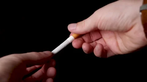 Caucasian hand breaks a cigarette in two halves, isolated black background. Stock Footage 146948837