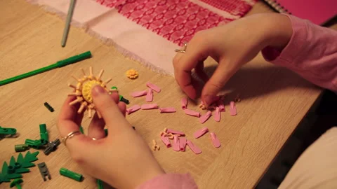 Caucasian hands meticulously assembling sunflower petals on table Stock Footage 335780294