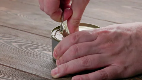 Caucasian hands opens tin can with pull ring on wooden surface Video stock 191914402