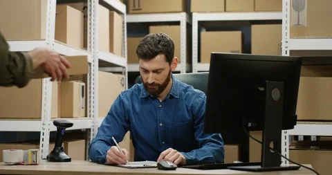 Caucasian handsome man sitting at table and working at computer in postal Stock Footage 125203640