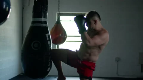 Caucasian handsome man wearing boxing gloves punching ahead on sandbag in the Stock Footage 155663653