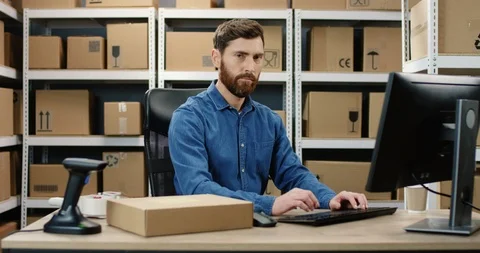 Caucasian handsome postman working at computer in post delivery office and Stock Footage 125218244