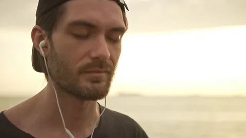 Caucasian happy bearded guy with cap on backward listening music using Stock Footage 80386280