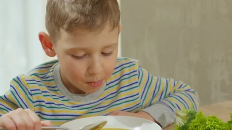 Caucasian hungry brown-haired boy eats soup with a spoon. Video stock 235729888