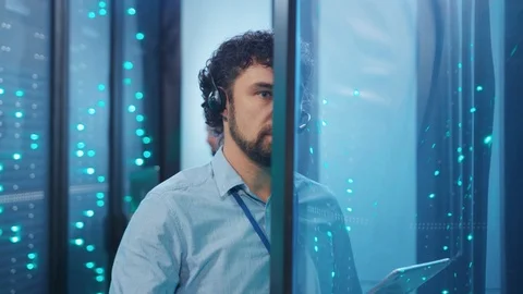 Caucasian IT engineer support with headset updating hardware in open rack server Video stock 119975496