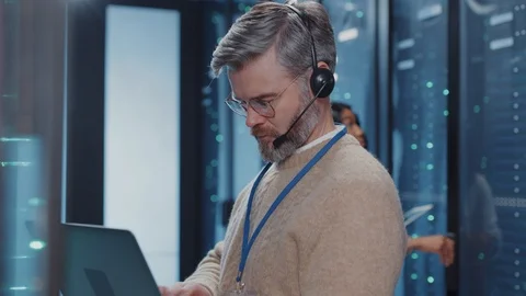 Caucasian IT operator looking at server racks collecting important data on Stock Footage 125404705