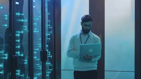 Caucasian IT technician walking in server rack corridor running maintenance Stock Footage 119232989