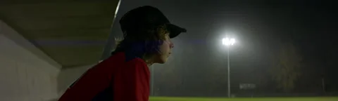 Caucasian kid boy baseball player posing on against flood lights a rainy evening Stock Footage 221837053