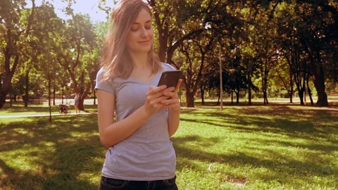 Caucasian lady typing message on mobile outdoors Stock Footage 129913309
