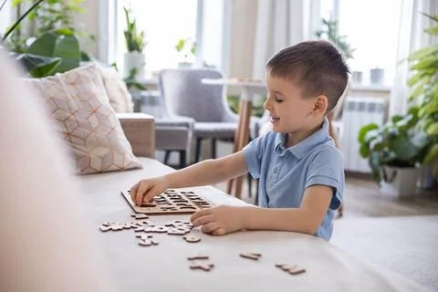 A Caucasian light-haired boy of five years old with blue eyes is putting Stock Photos