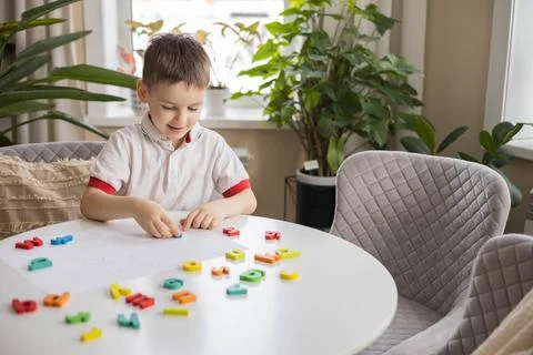 A Caucasian light-haired boy of five years old with blue eyes is putting Stock Photos