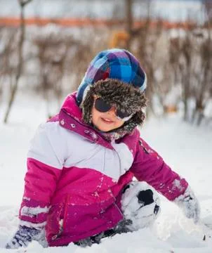 Caucasian little girl in winter clothes playing in the snow Stock Photos