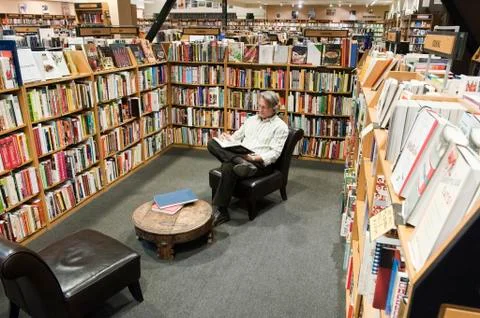 Caucasian male browsing through books in a large bookstore. Stock Photos