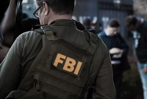 Caucasian male FBI agent wearing glasses in a green bulletproof vest with FBI Stock Photos