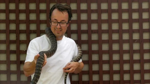 Caucasian male holds a python around his neck for the first time. Man Stock Footage 106999408