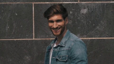 Caucasian male model posing in front of a wall styling his hair Stock Footage 87261196