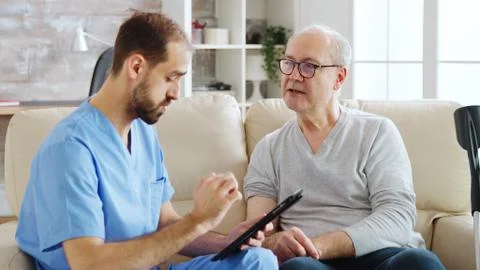 Caucasian male nurse talking with a nursing home patient about his health Stock Photos