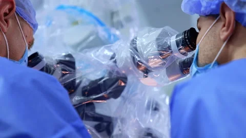 Caucasian male surgeons look at microscope covered in plastic. Stock Footage 309406357