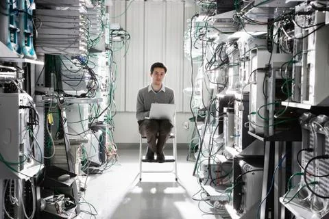 Caucasian male technician working on computer servers in a computer server farm. Stock Photos