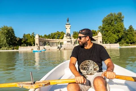 Caucasian male tourist rowing the boat in the Estanque Grande de El Retiro in Stock Photos