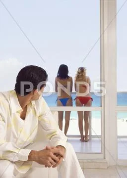 Caucasian man admiring women in bikinis Stock Photos