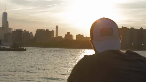 Caucasian man back view with a white cap looking at New York City from Brooklyn. Видео 110771199