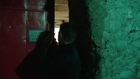 Caucasian man with backpack squeezes through an industrial door and runs through Stock Footage 199463035