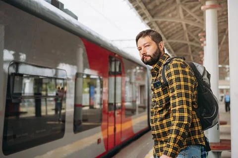 Caucasian man with backpack standing at platform going to take train. 写真素材