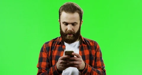 Caucasian man with a beard scrolling or texting on the smartphone in his hands Stock Footage 90376837
