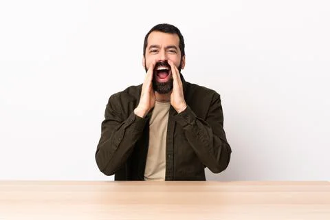 Caucasian man with beard in a table shouting and announcing something Stock Photos
