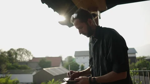 Caucasian man with a beard writes on his tablet some kind of information Stock Footage 246407077