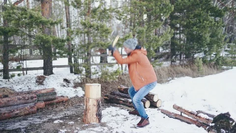 A Caucasian man in a brown jacket, hat, jeans and boots, holding an axe Stock Footage 128002422