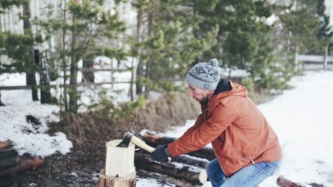 A Caucasian man in a brown jacket, hat, jeans and boots, holding an axe Stock Footage 128003617
