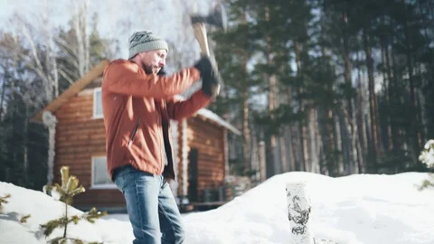 A Caucasian man in a brown jacket, hat, jeans and boots, holding an axe Stock Footage 128004963