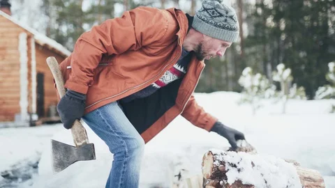 A Caucasian man in a brown jacket, hat, jeans and boots, holding an axe Stock Footage 128005447