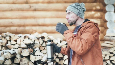 A Caucasian man in a brown jacket, hat and gloves drinking hot tea pouring it Stock-Footage 128006021