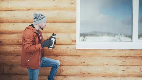 A Caucasian man in a brown jacket, hat and gloves drinking hot tea pouring it Stock Footage 128126703