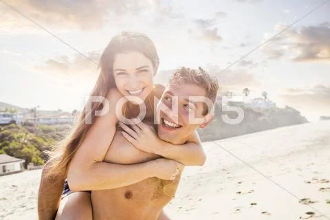 Caucasian Man Carrying Girlfriend On Beach