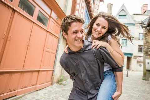 Caucasian man carrying girlfriend piggyback in village Fotos de archivo