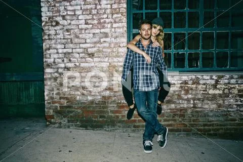 Caucasian man carrying girlfriend piggyback outdoors Stock Photos